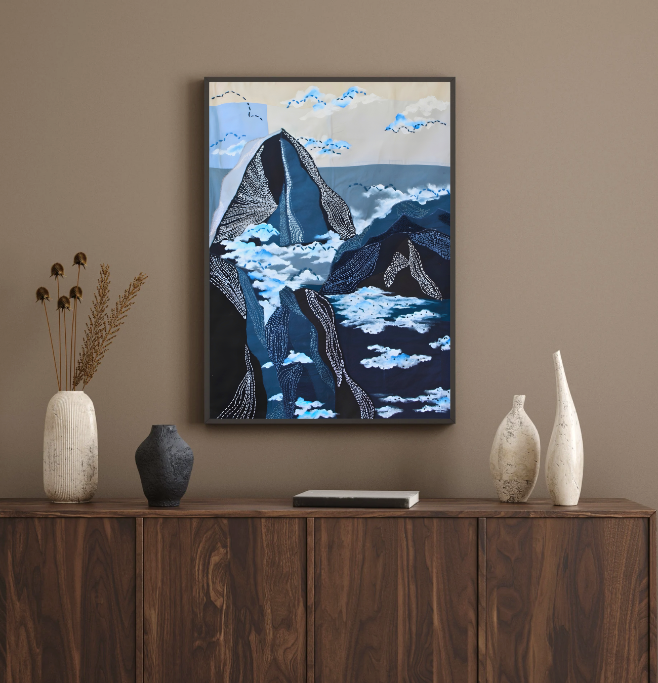 Handpainted fabric wall art depicting blue mountain landscape with intricate stitch detailing, styled above a wooden sideboard with ceramic vases - JOD