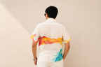 Person wearing a colorful shirt with abstract designs on a plain background