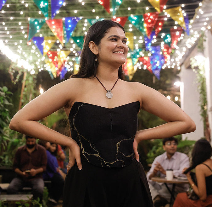 Black strapless corset top with minimal gold artwork, modern party top styled for evening celebrations.