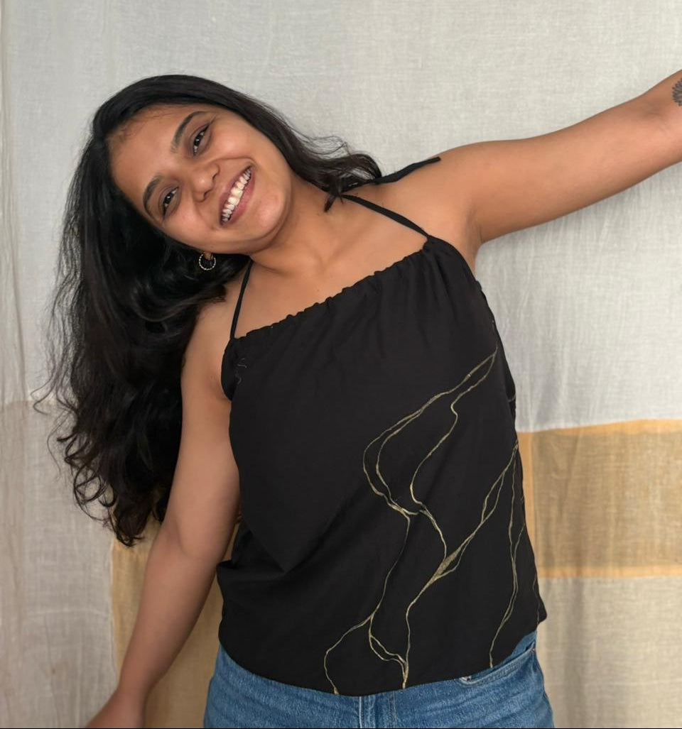 Woman wearing a black top with gold designs and blue jean