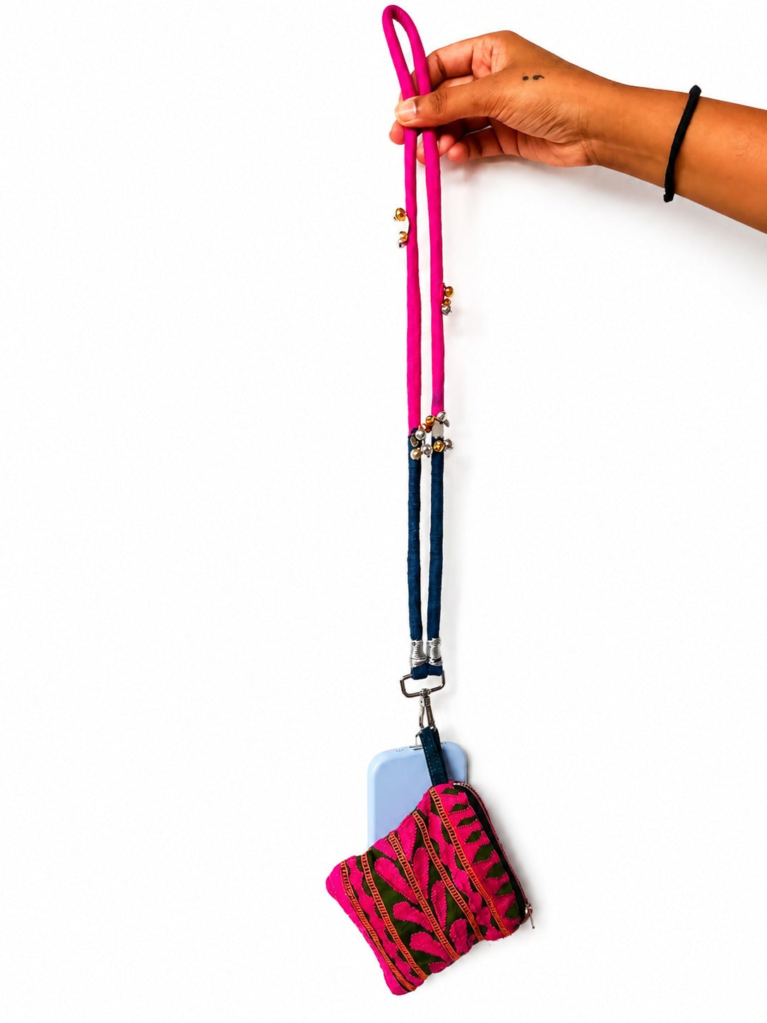 A hand holding a bright pink and navy blue fabric phone strap with a matching patterned pouch containing a light blue phone, set against a plain white background.