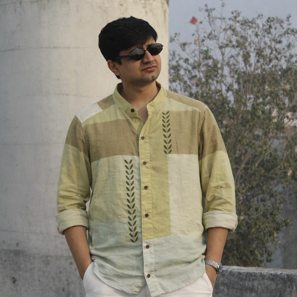 Man wearing a patterned shirt standing on a rooftop with buildings in the background