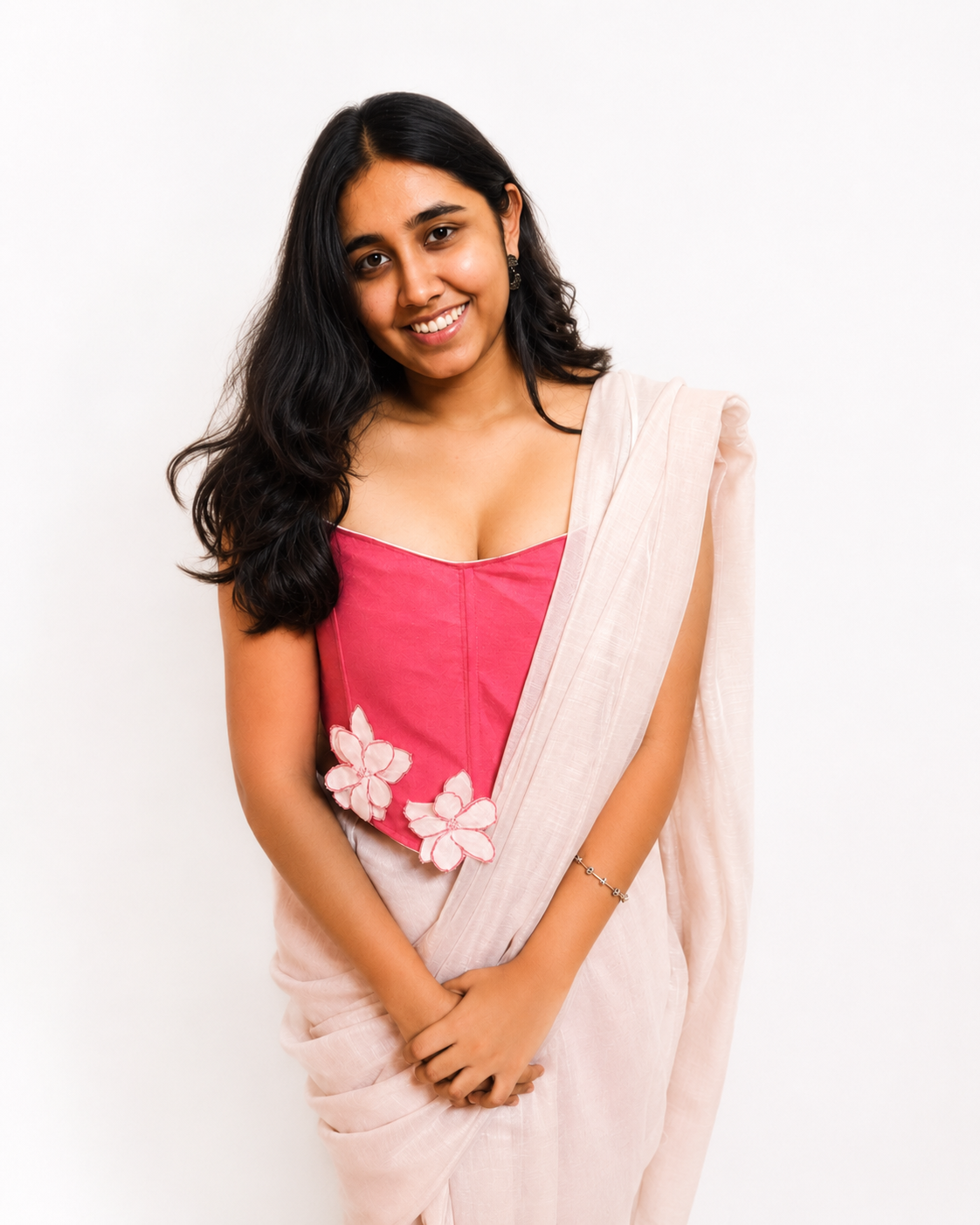 Woman wearing a pink floral corset blouse and beige saree with floral details on a white background