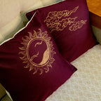 Maroon pillows with gold painted details on a beige couch.