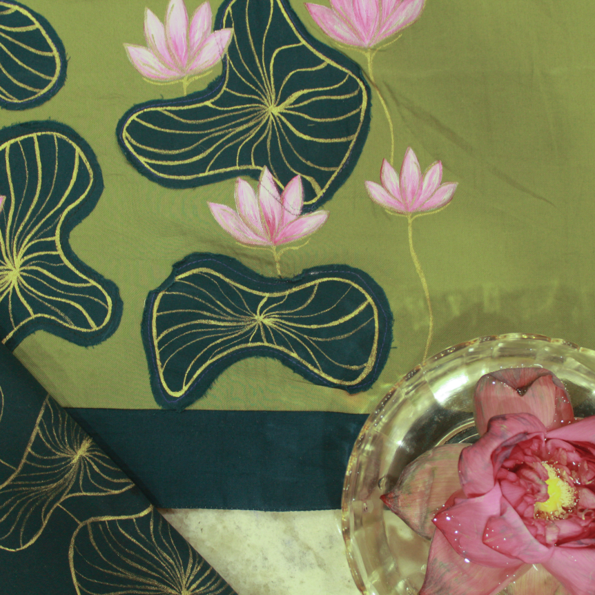 Green fabric with pink floral hand painting and a pink flower in a glass dish.