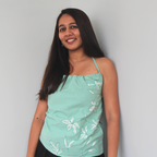 Woman wearing a light green top with floral embroidered and hand painted details