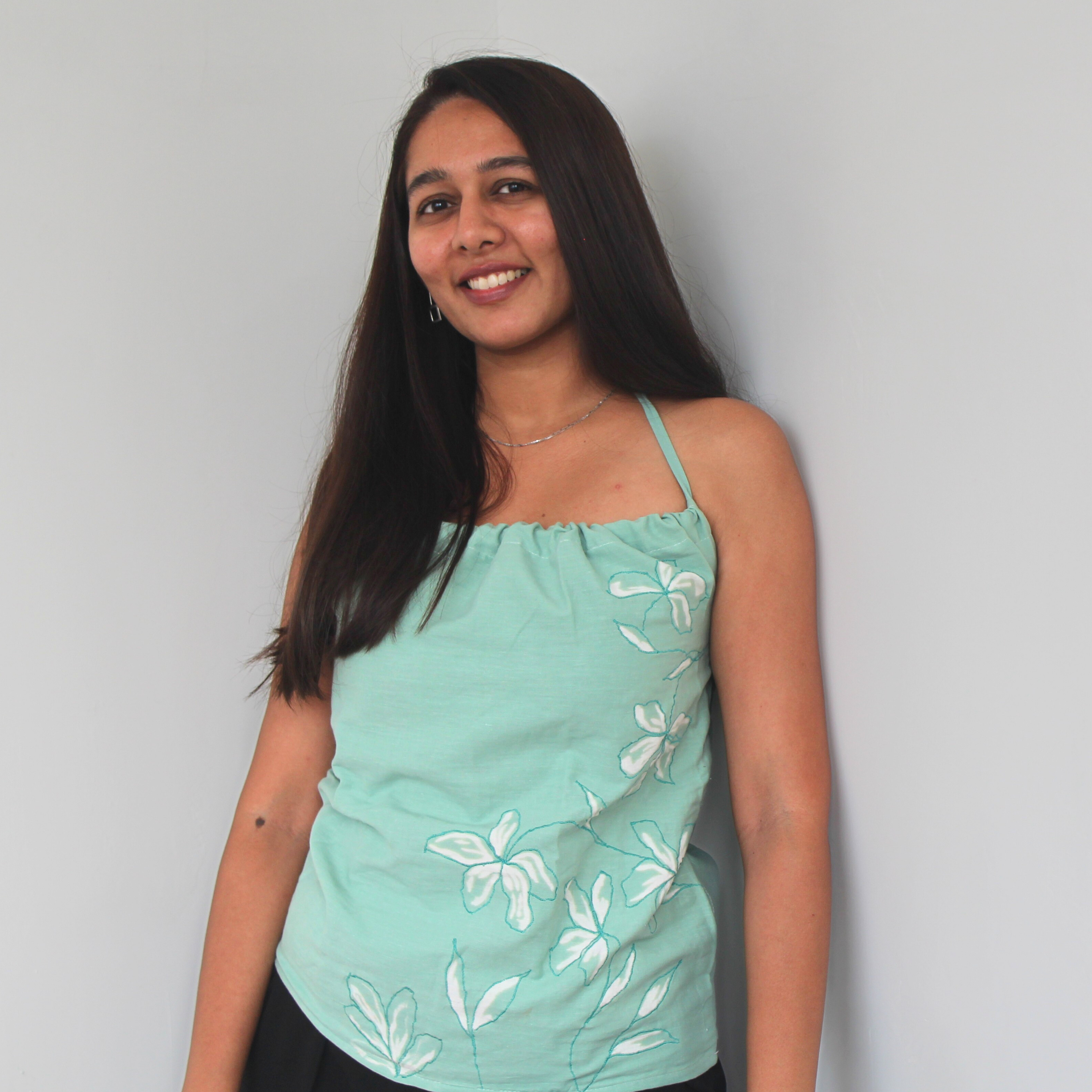 Woman wearing a light green top with floral embroidered and hand painted details