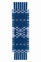 A woven rectangular textle with fringe ends, featuring a geometric pattern in shades of navy blue, medium blue, and light blue on a white background.
