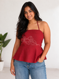 Woman wearing a red peplum halter top with floral embroidery and blue jeans against a white background