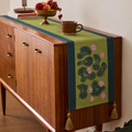 Wooden sideboard with a decorative table runner featuring floral patterns and tassels.