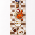 Chexed table runner with a tabke setting of brunch with white plates and pastry