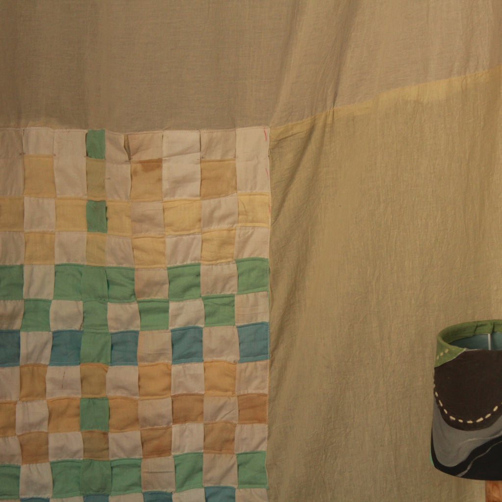 Woven curtain with geometric pattern and a lampshade in the foreground.