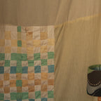 Woven curtain with geometric pattern and a lampshade in the foreground.