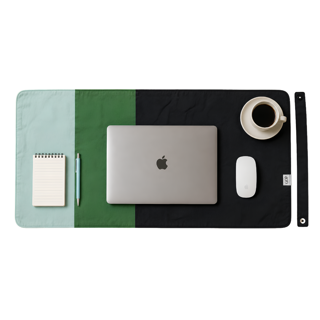 A rectangular desk mat with a three-tone color-block design in mint green, forest green, and black, styled with a silver laptop, white mouse, coffee cup, notepad, and pen on a white background.
