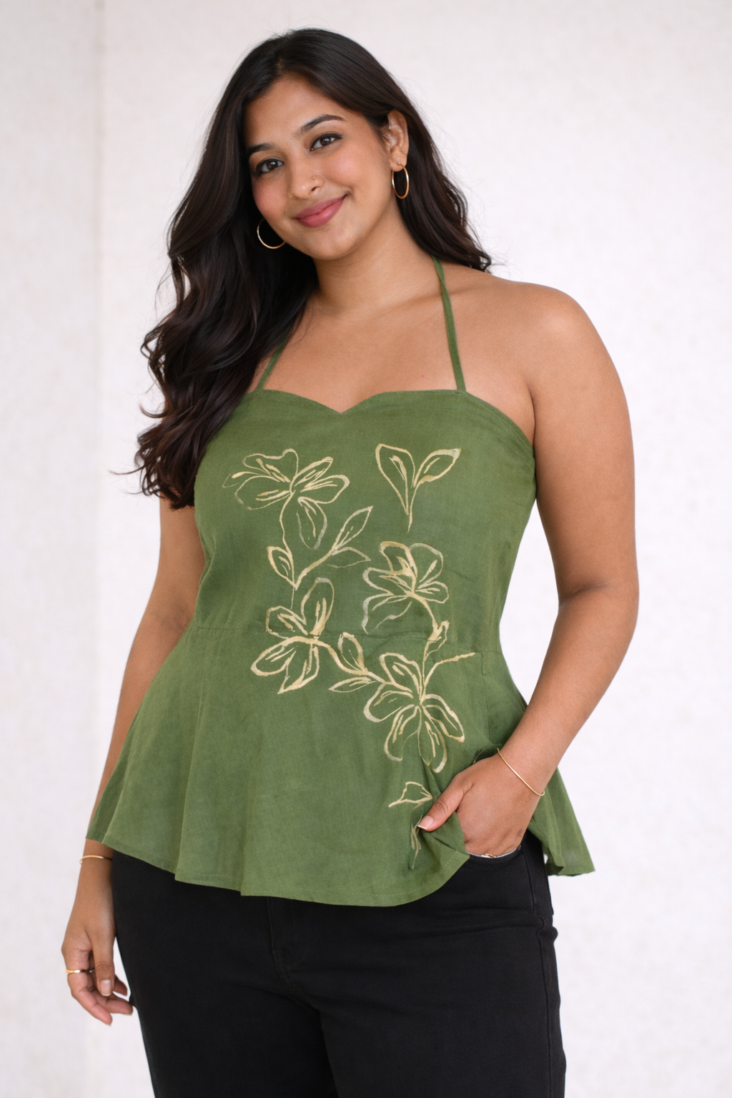 Woman wearing a green floral embroidered top against a white background