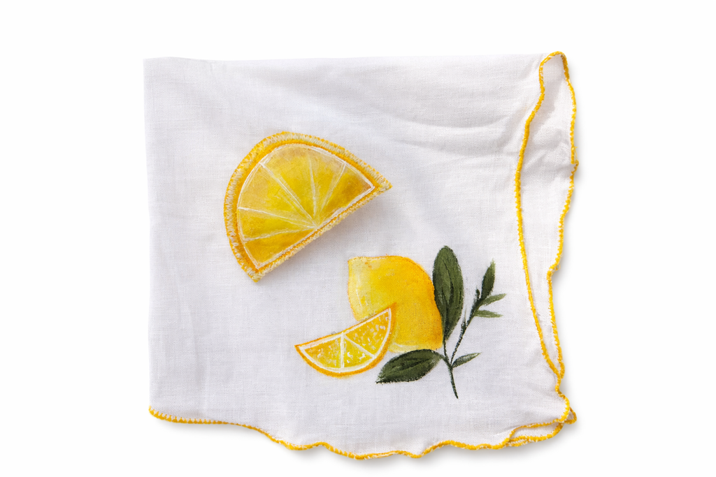 White handkerchief with hand painted yellow lemon slices and green leaves on a white background