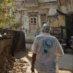 Person walking down a sunlit street with old buildings and trees
