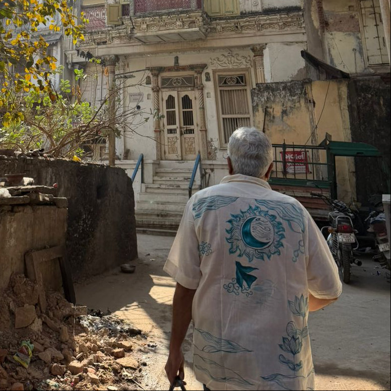 Person walking down a sunlit street with old buildings and trees