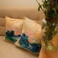 Decorative pillows with floral designs on a beige sofa next to a vase of white flowers.