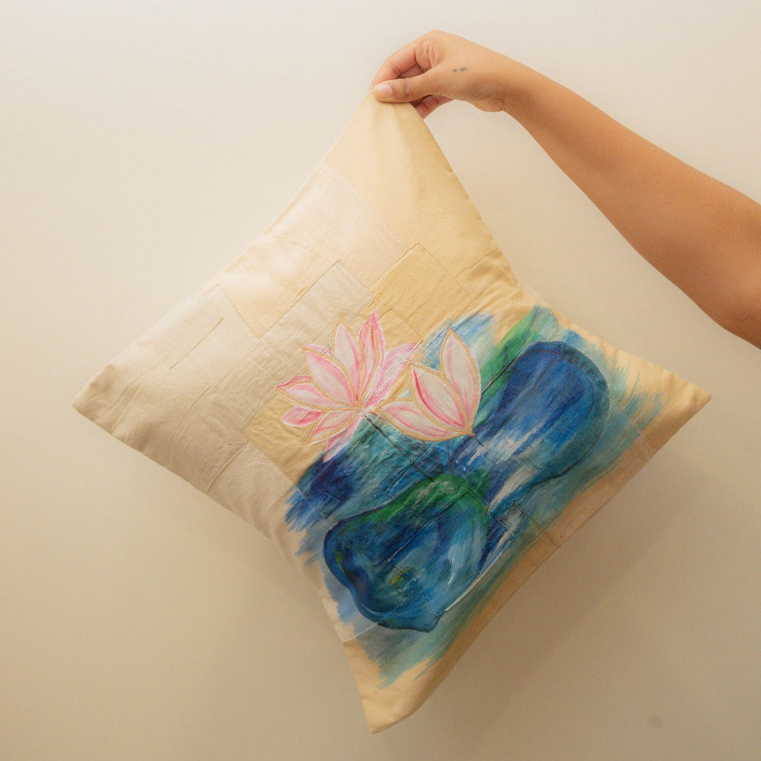 Hand holding a pillow with a lilly pads design of a pink lotus flower