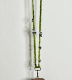 Green braided lanyard with metal clips on a white background