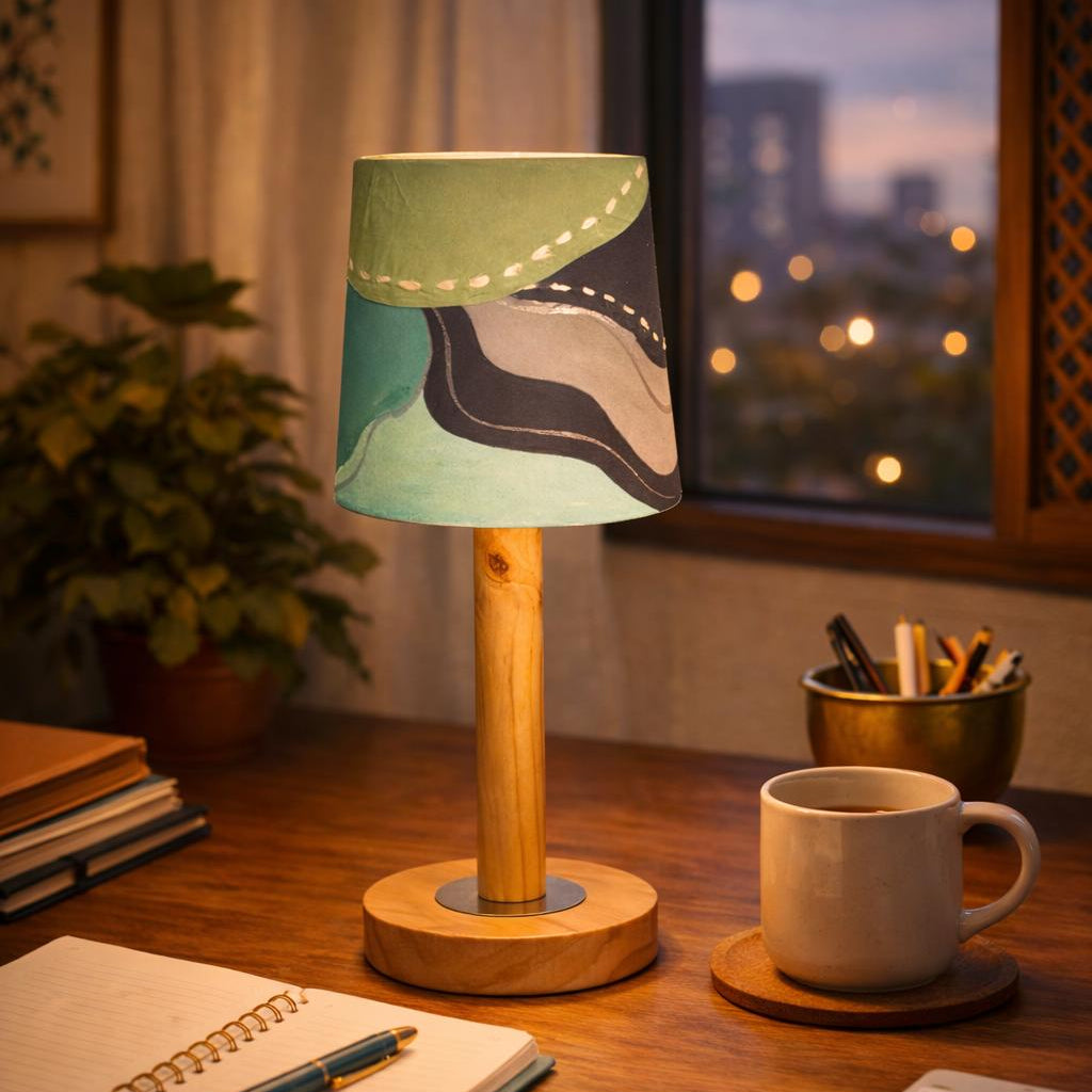 Desk with a lamp, mug, notebook, and pen, with a cityscape view through a window.