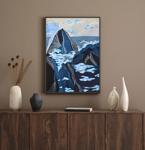 Framed mountain inspired artwork on a wall above a wooden cabinet with decorative vases.