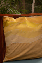 Yellow quilted pillow on a wooden chair with plants in the background