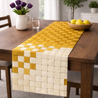 Yellow and white woven table runner on a wooden table with a vase of purple tulips and a bowl of lemons.