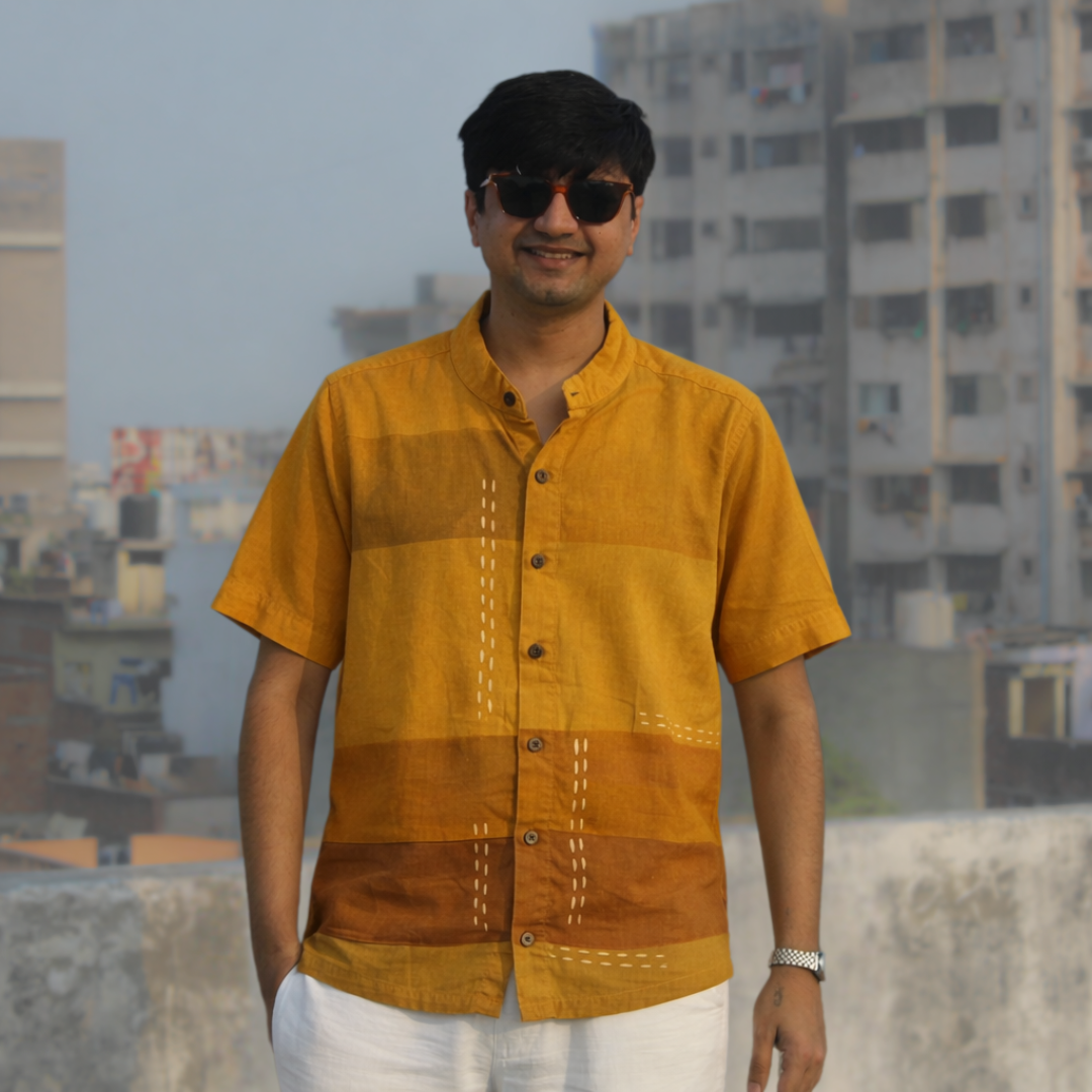 Man wearing a mustard yellow shirt with a cityscape background