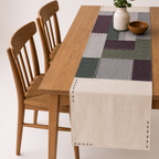 Dining table with a patchwork table runner and wooden chairs.