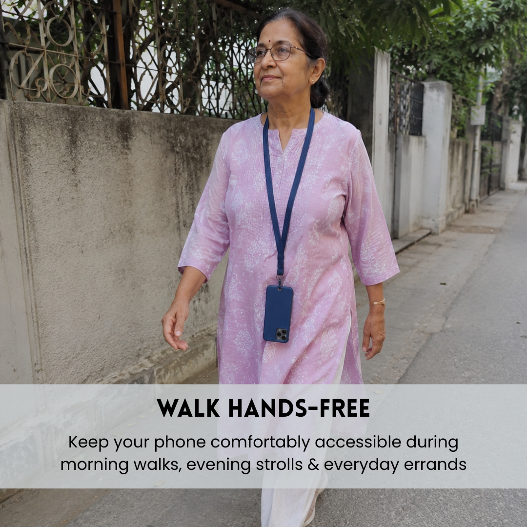 A woman walking outdoors on a sidewalk wearing a light pink patterned kurta and a navy blue lanyard with a phone holder. A text banner at the bottom reads 'WALK HANDS-FREE' with additional descriptive text.