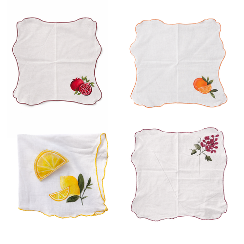 Four hand painted table napkins with fruit designs on a white background