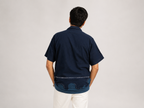 Person wearing a navy blue shirt with white pants on a plain background
