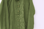 Green shirt with intricate white embroidery on a white background