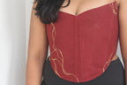 Red strapless top with gold accents worn by a person against a neutral background