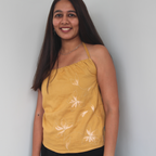 Woman wearing a mustard sleeveless top with white floral patterns
