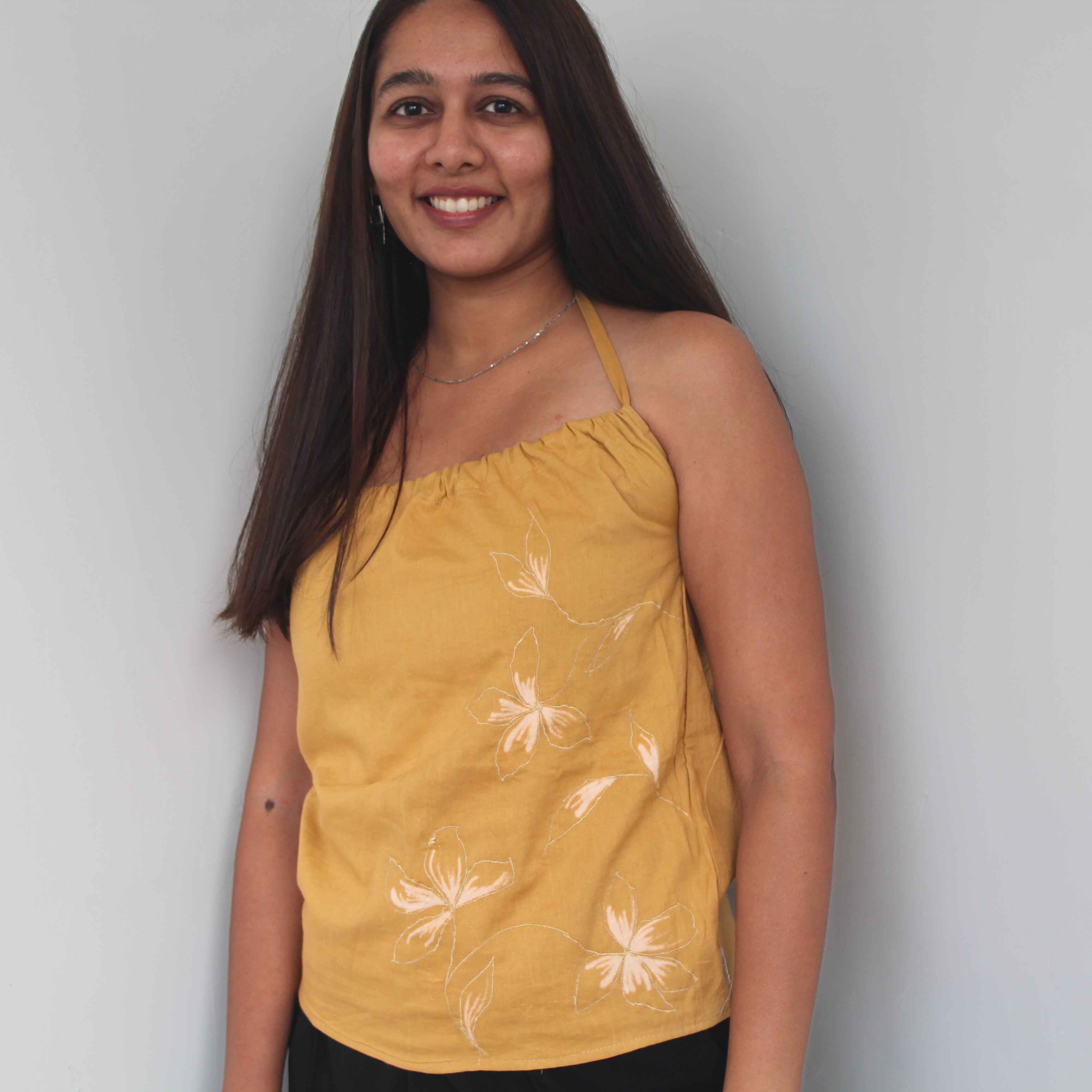 Woman wearing a mustard sleeveless top with white floral patterns