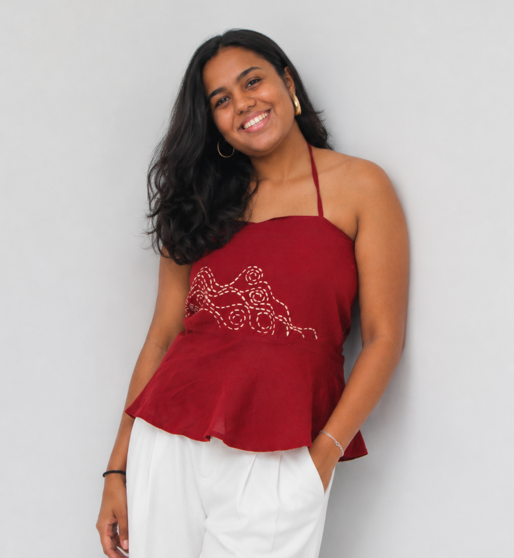 Woman wearing a red halter top with white pants against a plain background
