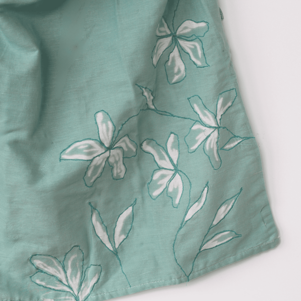 Teal sleeveless cotton top with floral detail, lightweight summer top styled for vacations and relaxed outfits.