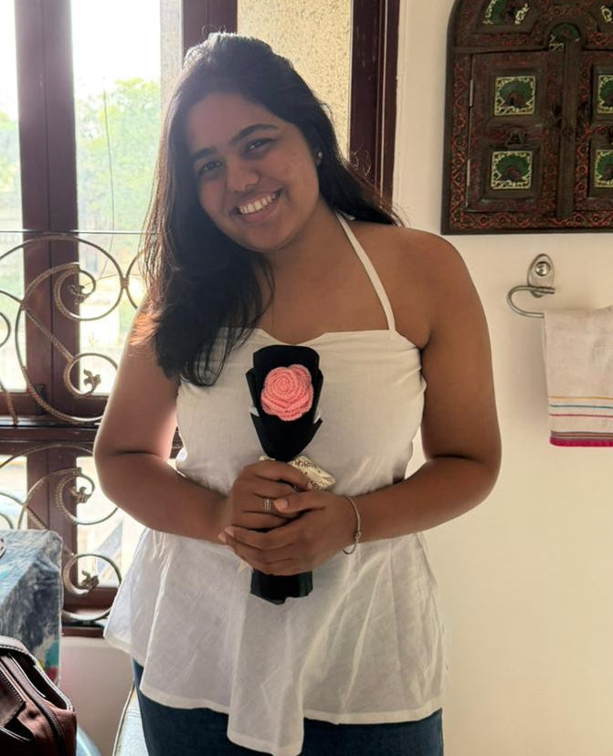 Woman wearing a summer essential hakter neck top in white and holding flower