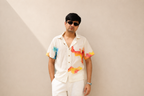 Person wearing a colorful shirt with abstract designs on a plain background