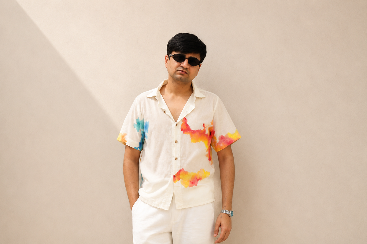 Person wearing a colorful shirt with abstract designs on a plain background