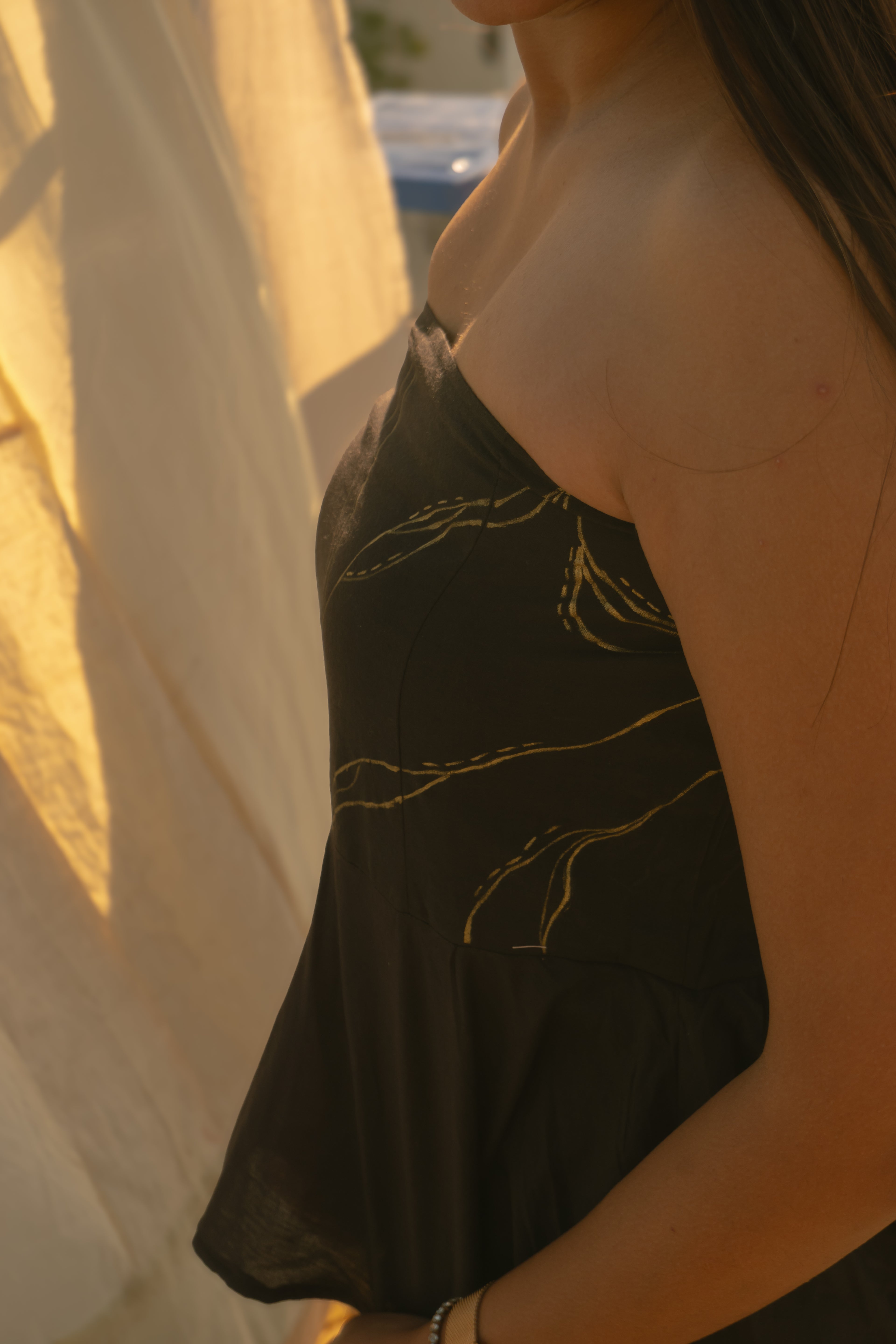 Person wearing a black Top top with gold detailing
