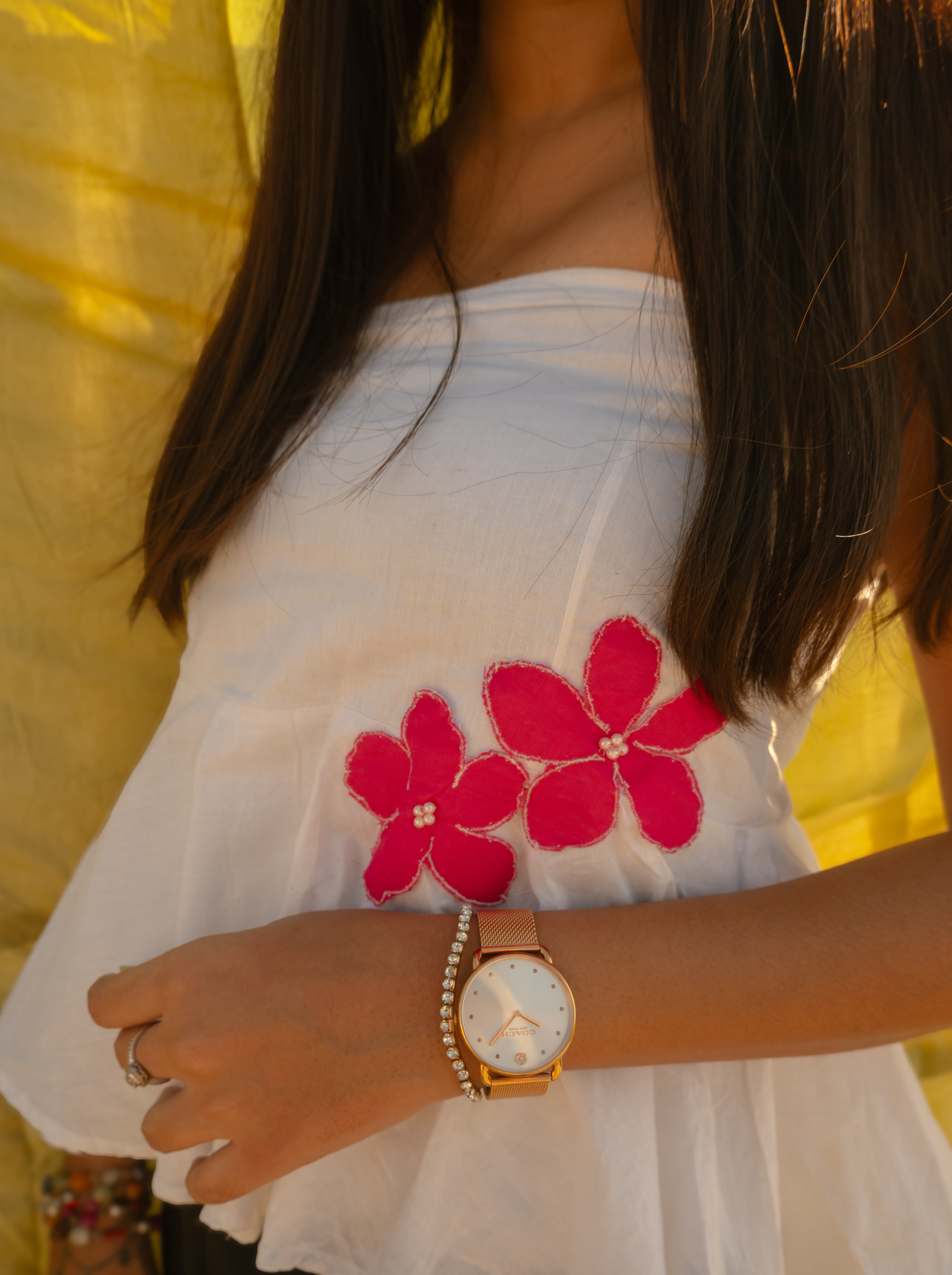Woman wearing a minimal floral strapless cotton top with handmade flower accents, lightweight summer tube top.