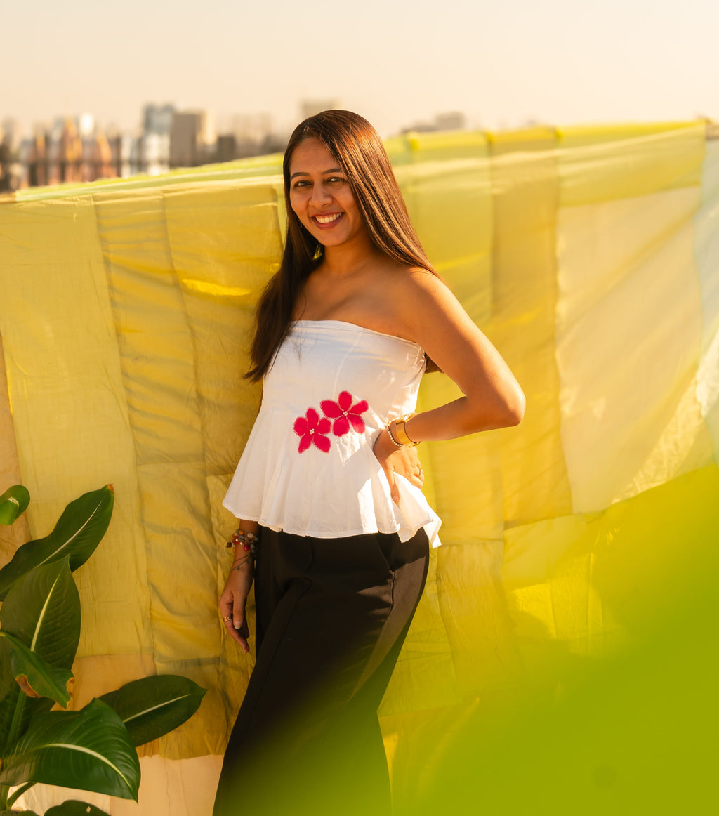 Woman wearing a floral strapless peplum top with hand crafted flower detail, lightweight summer tube top for casual and vacation wear.