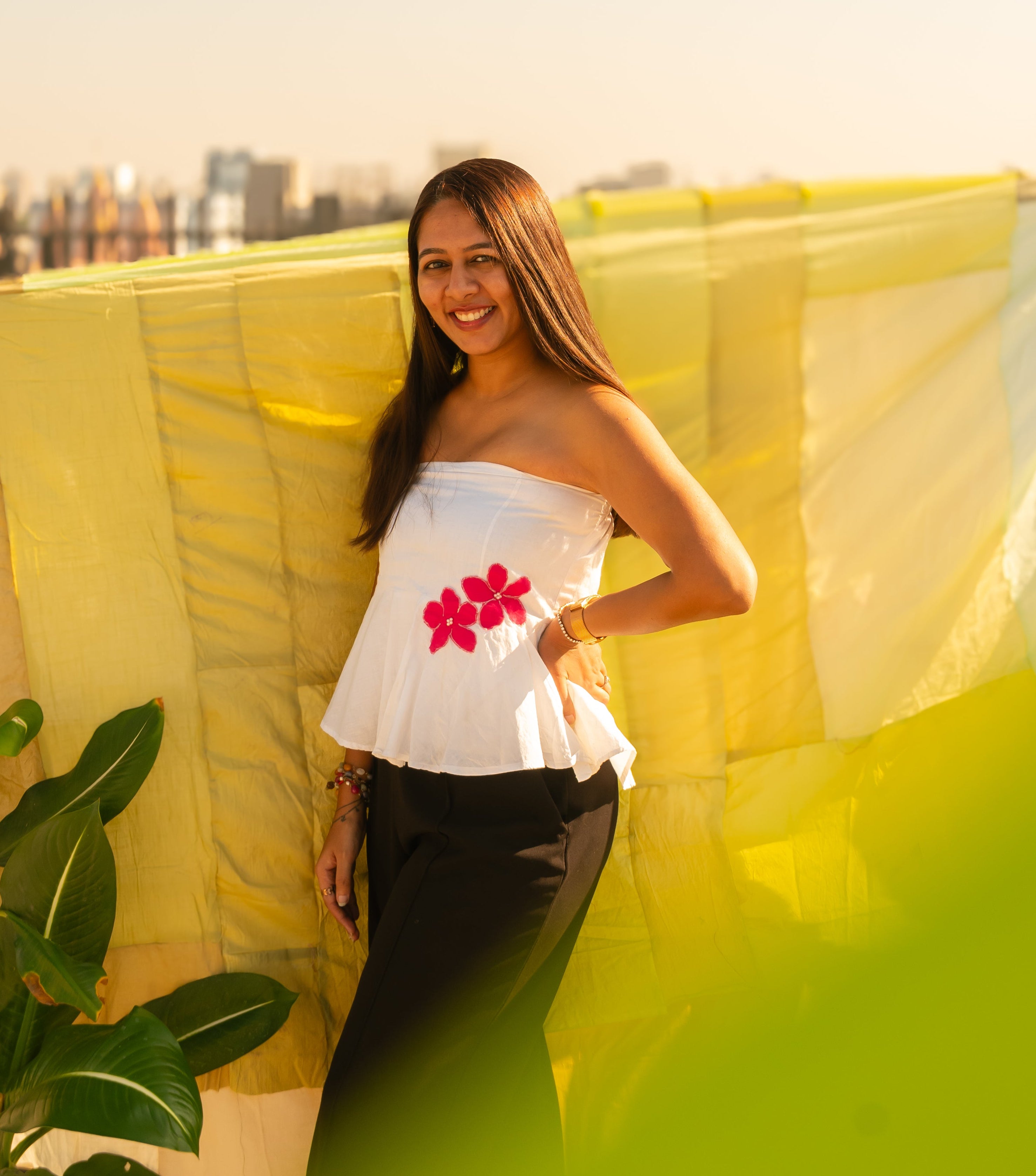Woman wearing a floral strapless peplum top with hand crafted flower detail, lightweight summer tube top for casual and vacation wear.