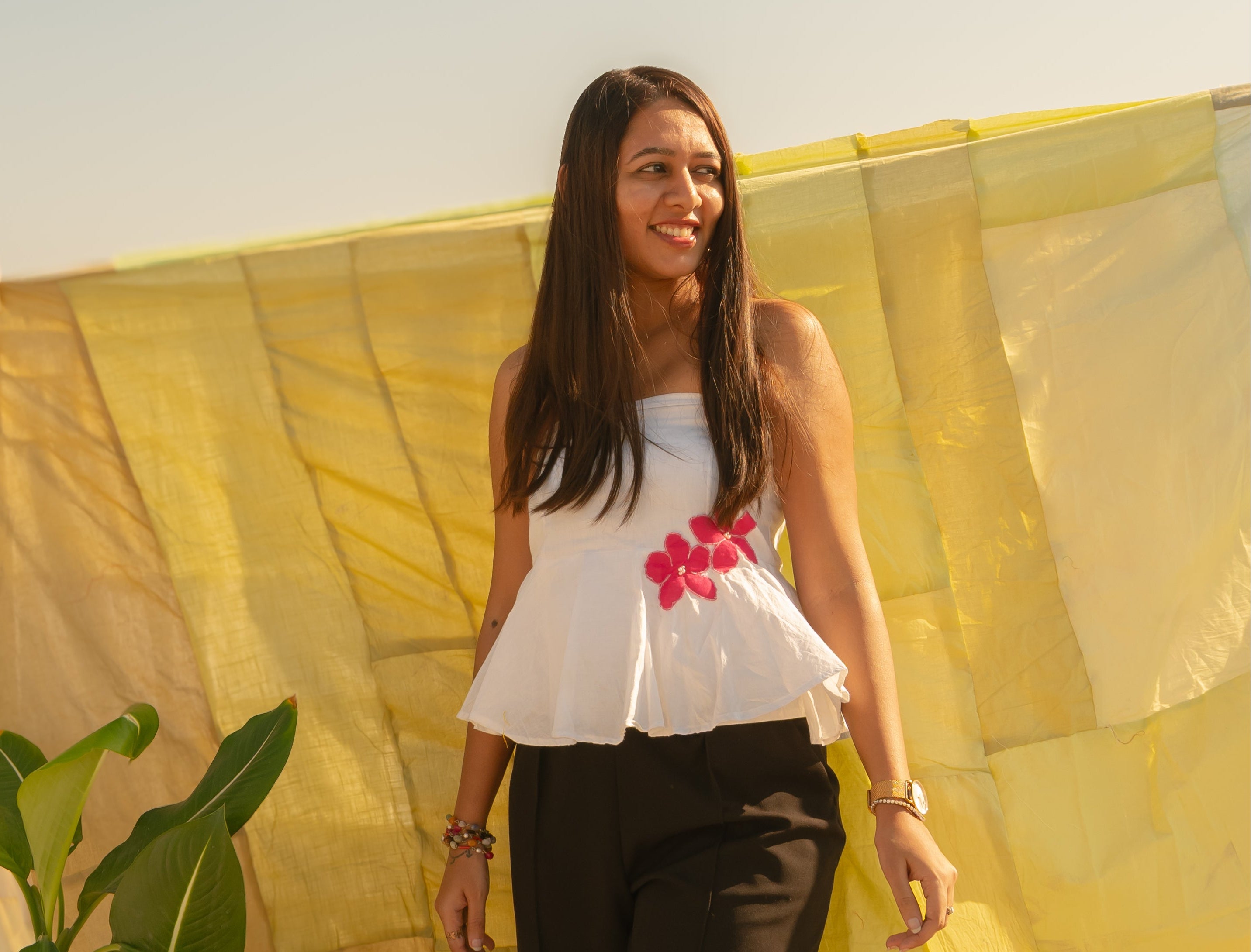 Woman wearing a strapless floral summer top with handcrafted flower accents, lightweight tube top for warm weather styling.