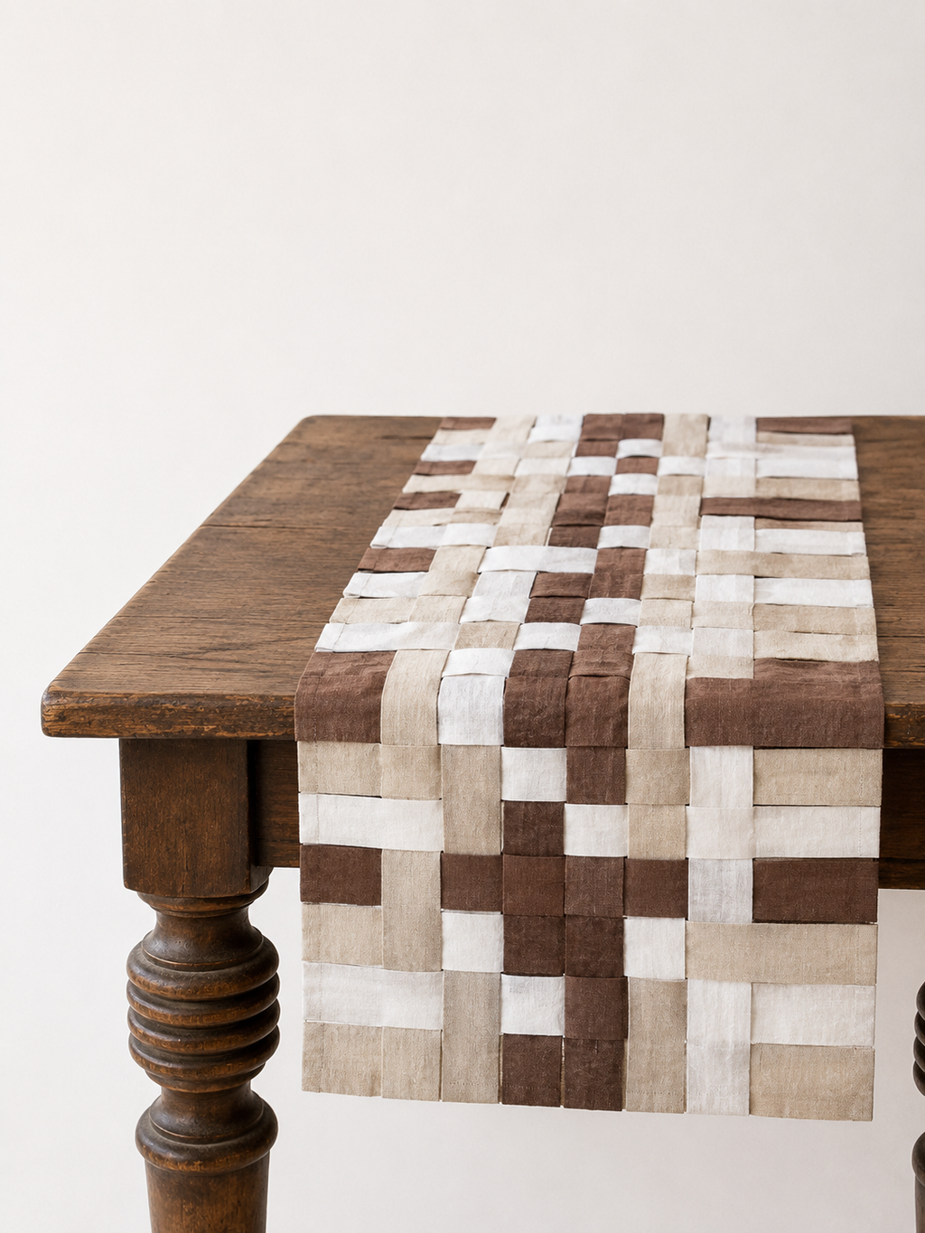 Woven patterned table runner on a wooden table with a white background