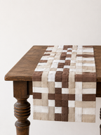 Woven patterned table runner on a wooden table with a white background